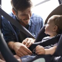 Father Putting Baby In Car Seat Stock Photo