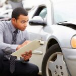 Insurance Adjuster Looking At Car Stock Photo